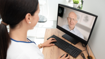 Virtual nursing in aged care: A nurse using her computer to communicate with a patient
