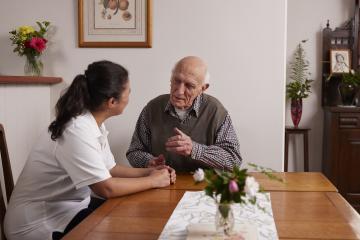 New training for Support at Home now available - aged care worker and elderly person sitting talking.