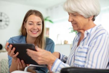 Young female assisting elderly women with iPAD