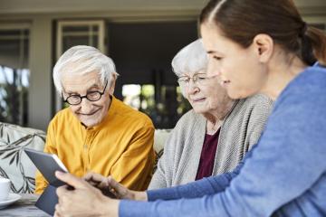 Young women showing an elderly couple how to use their iPad