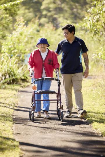 Elderly women walking with her carer and a walking aid