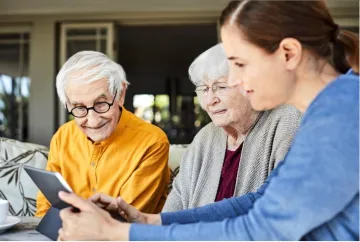 Elderly couple with family member looking at a Ipad