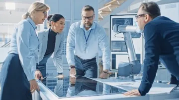 Photographic image of 4 people standing around a table discussing matters about research
