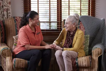 Elderly women holding hands with her carer