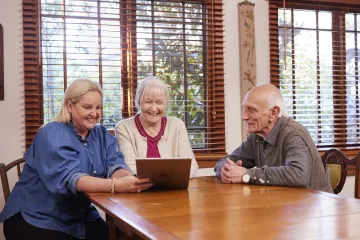 Photo featuring 3 people at a table using a laptop
