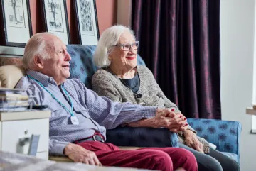 Elderly couple sitting together holding hands