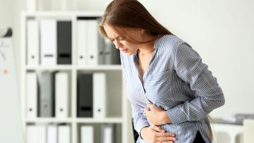 Woman holding her abdomen and bending over in pain