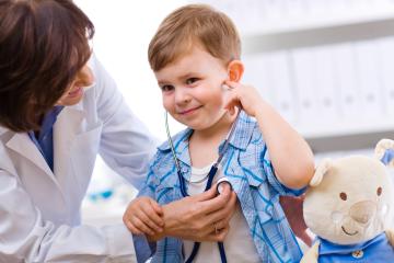 Young boy with doctor listening to own heart