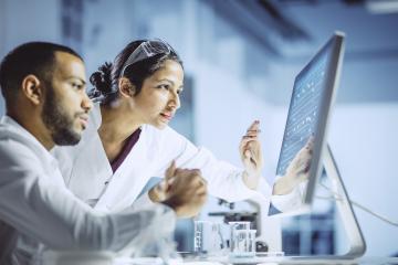 Male and female scientists looking at a computer