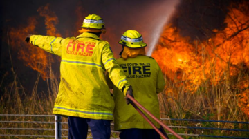 Two firefighter and bushfire flames