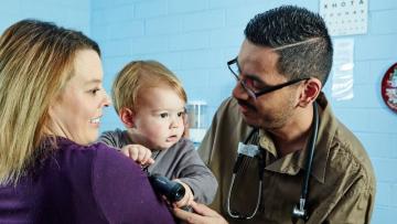 Doctor assessing child in mother's arms
