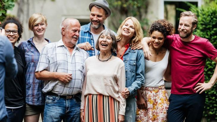 Large family group, with older couple at the centre, having a photo taken in the garden.