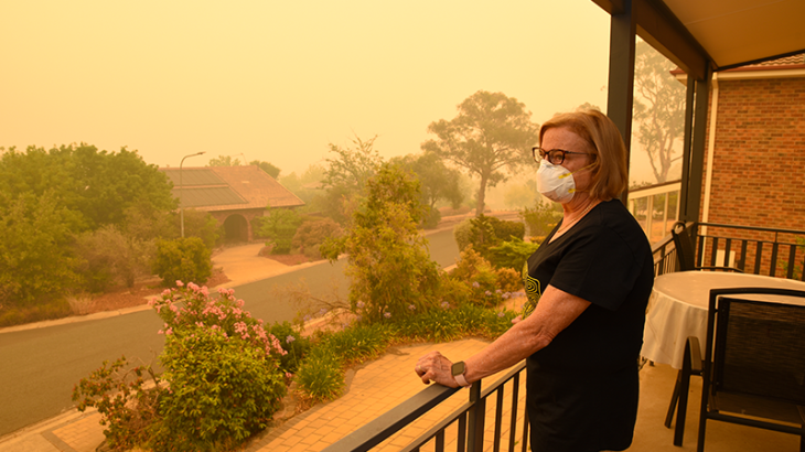 Image of woman standing in polluted air wearing an N95 face mask. 