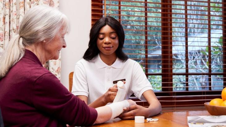 Image of a nurse bandaging an older person's arm