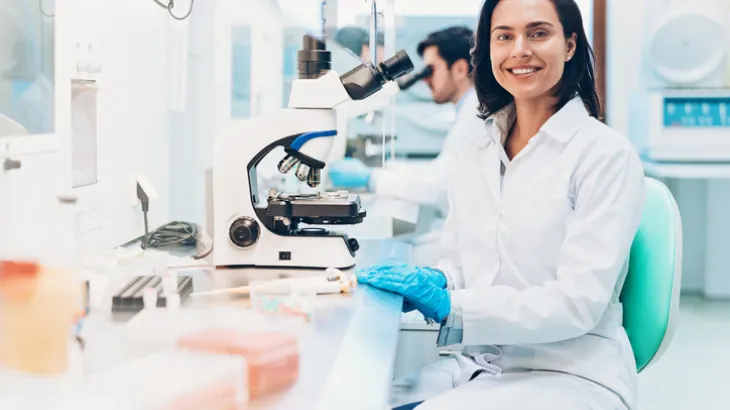 Researcher sitting at a workstation with a microscope