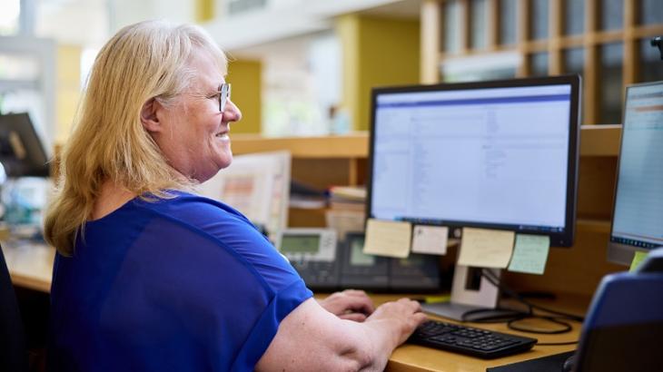 Female office worker typing and viewing desktop screens