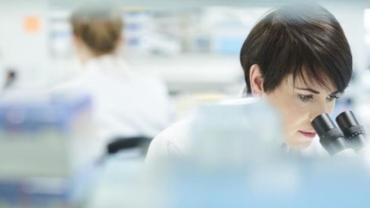 Female lab technician looking through microscope