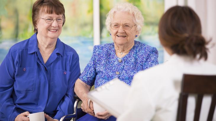 An aged care resident and an aged care worker smiling 