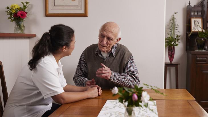 New training for Support at Home now available - aged care worker and elderly person sitting talking.