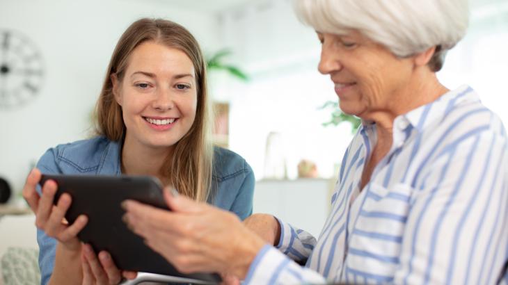 Young female assisting elderly women with iPAD