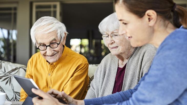Young women showing an elderly couple how to use their iPad