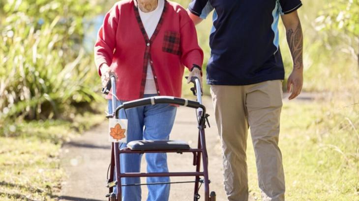 Elderly women walking with her carer and a walking aid