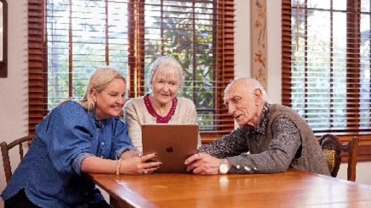 Three elderly people look at a laptop