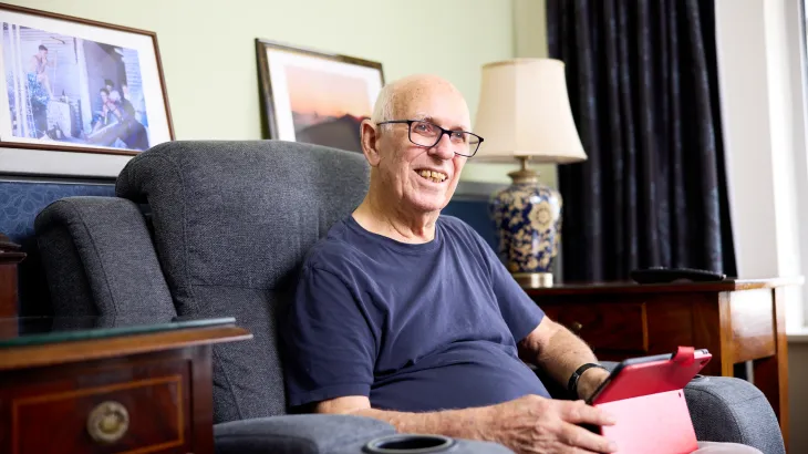 Male aged care resident in his room with a electronic device