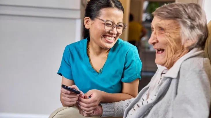Elderly women and her female carer laughing together