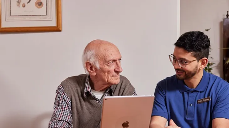 Photograph of an elderly male talking to a male carer