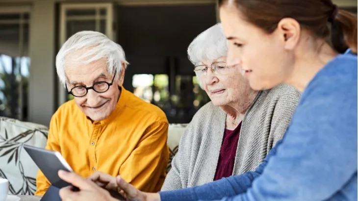 Elderly couple with family member looking at a Ipad