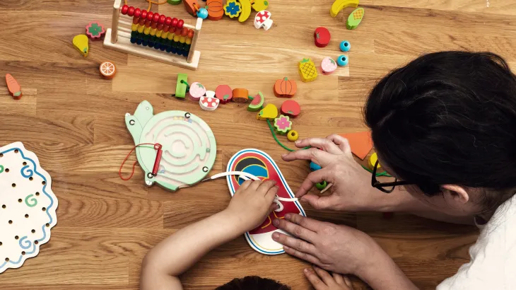 A child and early childhood educator playing with toys at a table