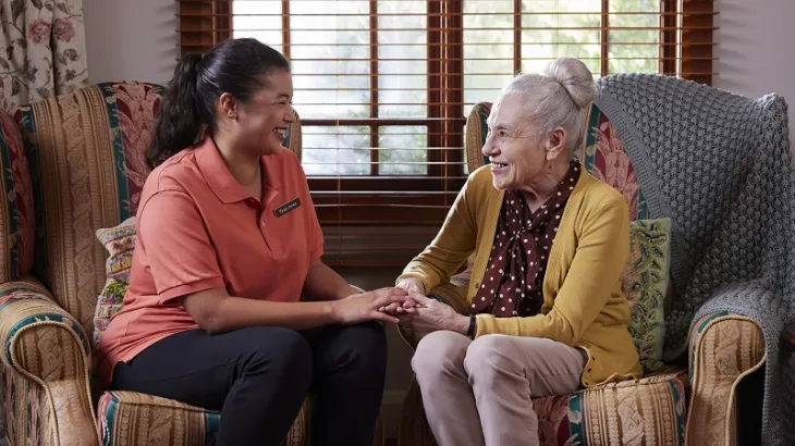 Elderly women holding hands with her carer