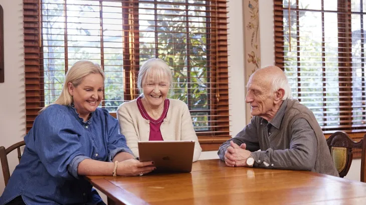 Photo featuring 3 people at a table using a laptop