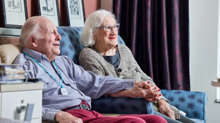 Elderly couple sitting together holding hands