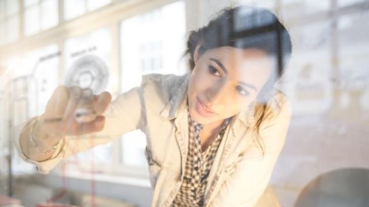 Woman writing on a clear whiteboard