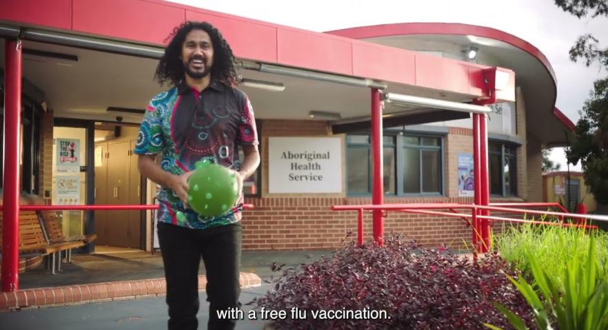 First Nations man smiling and holding a soccer ball outside an aboribinal health service