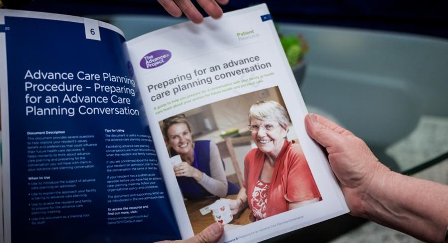 Hands hold open a pamphlet that is displaying information about advance care planning procedures and preparing for an advance care planning conversation. 