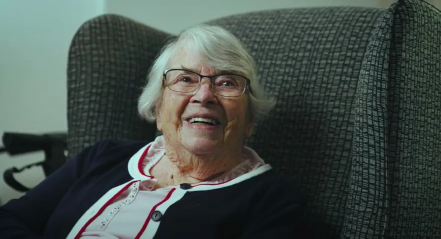 older woman smiling sitting armchair.