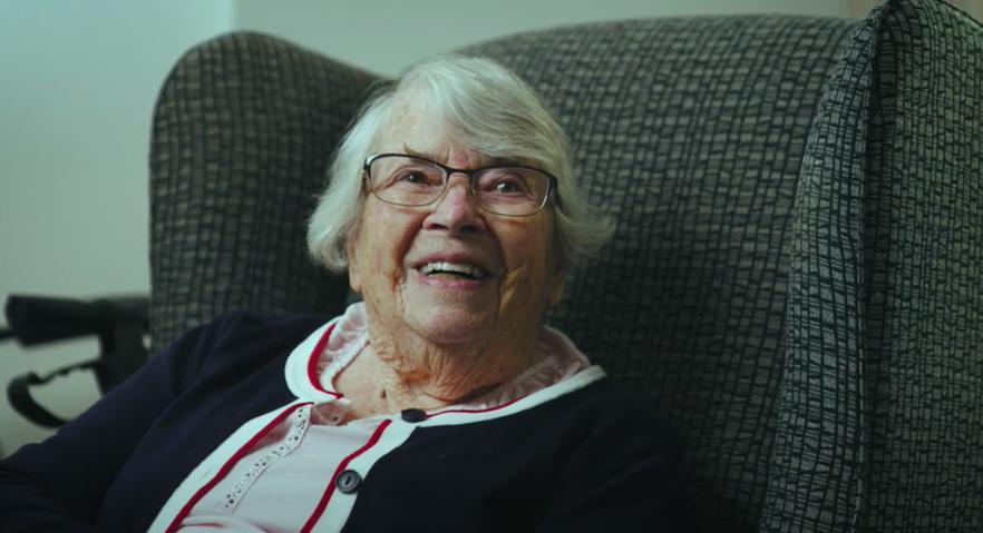 older woman smiling sitting armchair.