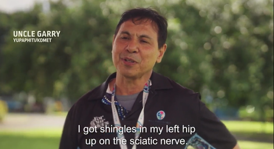 Man in black polo top with a lanyard around his neck being asked about his experience with Shingles