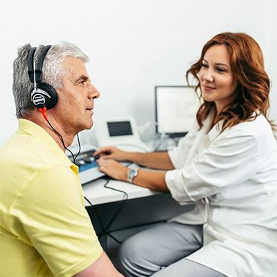 Man wearing headphones during a hearing test with a woman in a lab coat with long hair