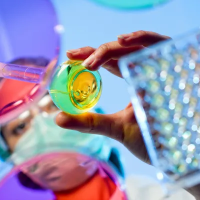 Image of female Laboratory technician added liquid to a vile. This view is from under a glass desk