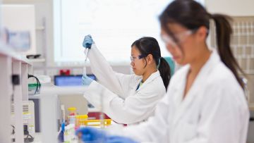 Photo is of a researcher dropping liquid into a tube.