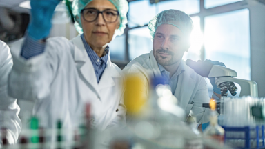 Older female scientist and young male scientist at work in lab