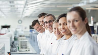 Laboratory staff in white coats smile for the camera